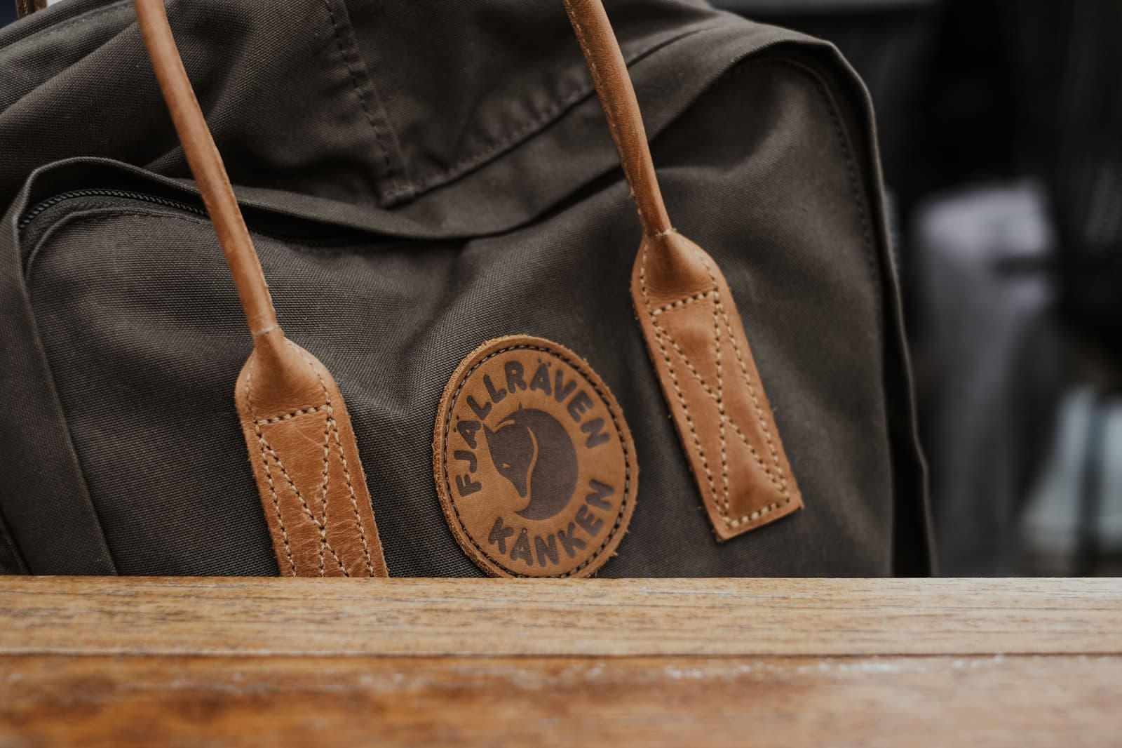 A tan full-grain leather bag on a warm wooden surface in soft light