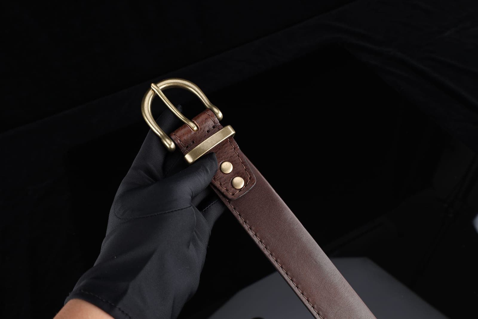 A coiled brown leather belt with a brass buckle